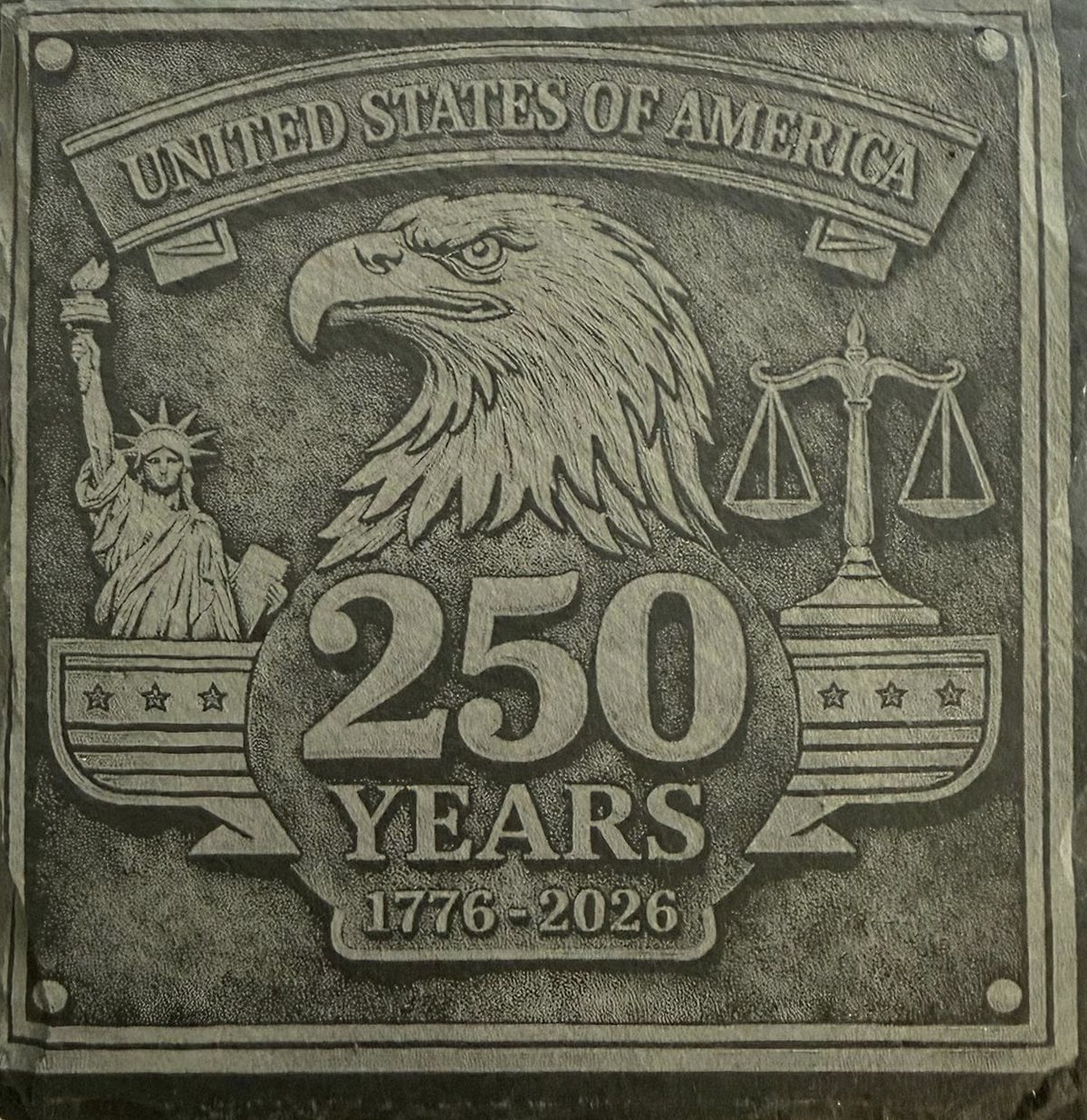 A square slate plaque engraved 'United States of America, 250 years, 1776–2026' with a bald eagle, the Statue of Liberty and the scales of justice