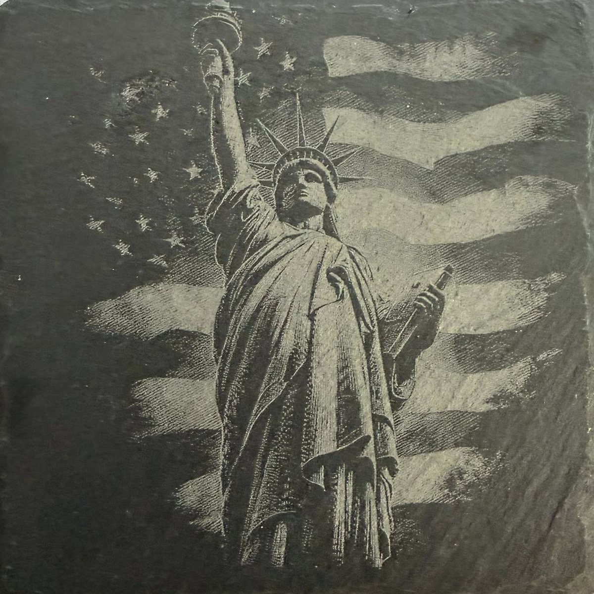 A square of natural slate engraved with the Statue of Liberty in front of a waving American flag