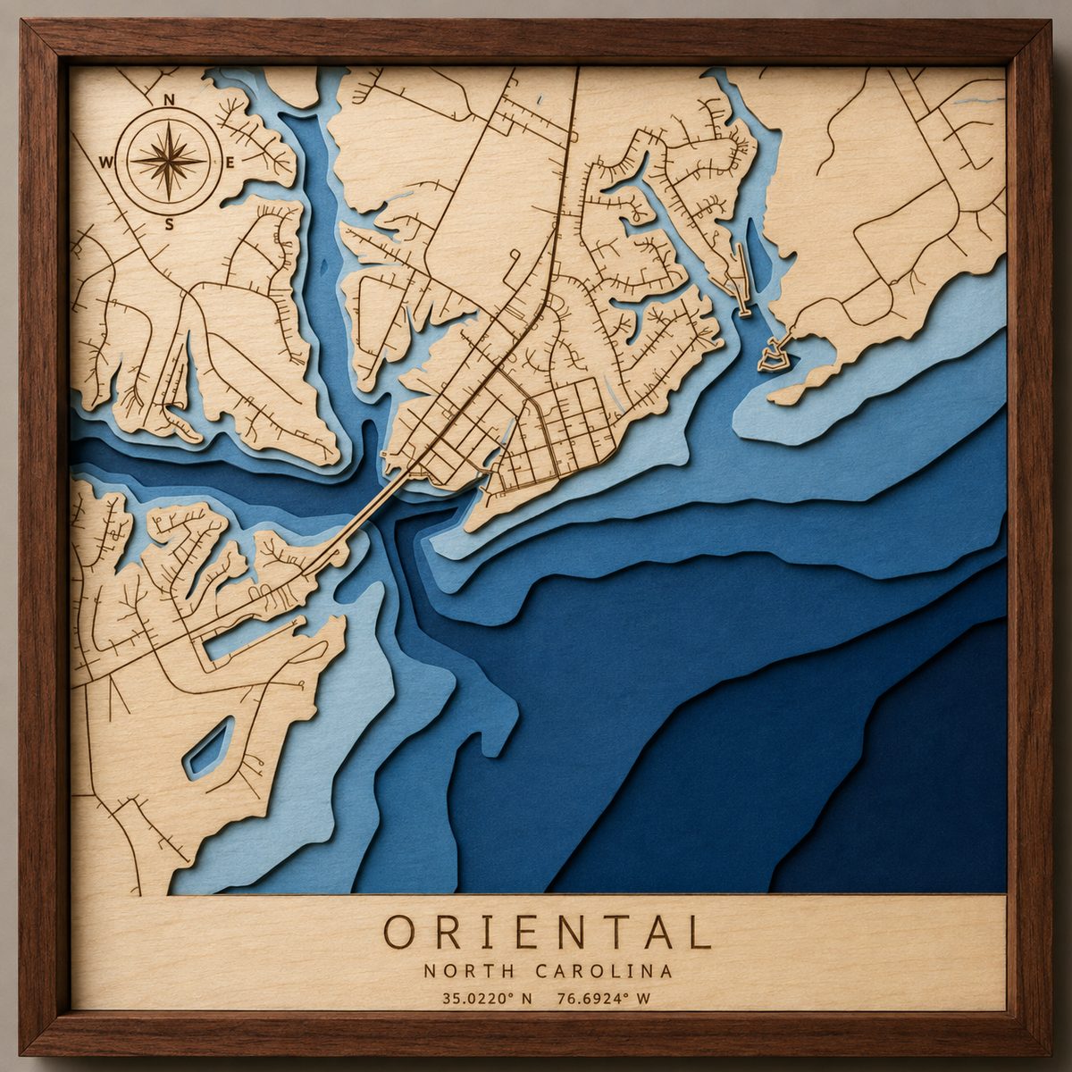 A framed layered wood map of Oriental, North Carolina: pale wood land with engraved streets over five shades of blue water