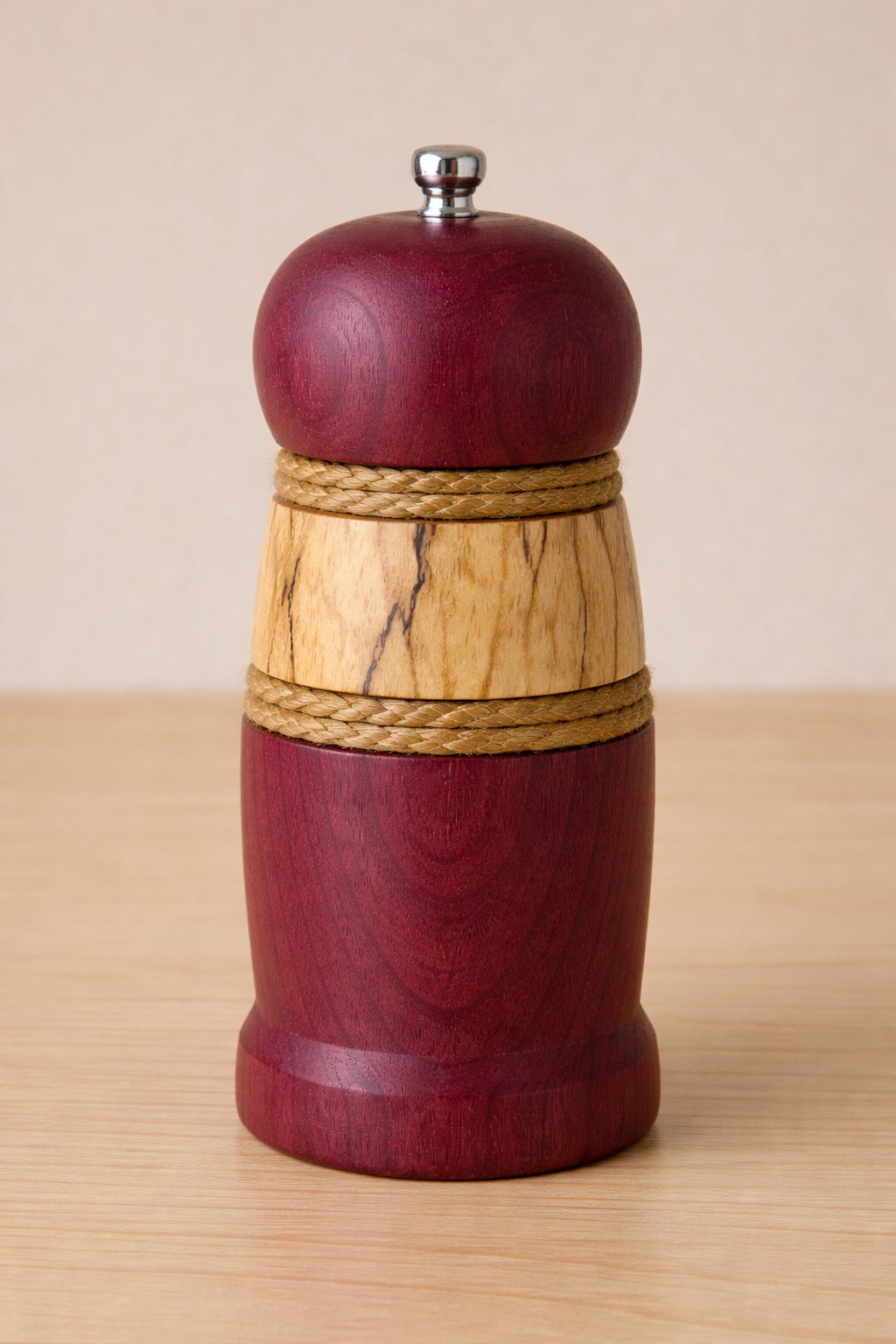A shorter purpleheart pepper mill with a round cap and the same spalted maple and cord band
